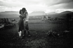 A couple embracing at Syðri-Reykir farm in Biskupstungur, with the Golden Circle mountains and Brúarárskörð in the background — family archive photograph.